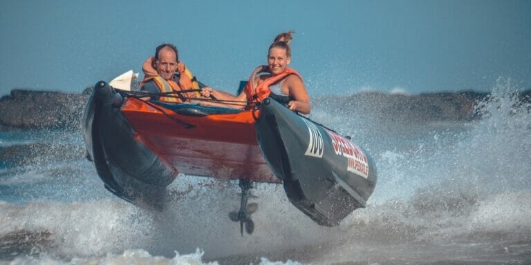 a man and a woman together in a thundercat racing boat, jumping over a wave