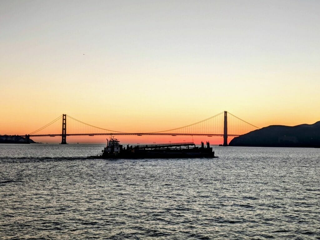 View of the Golden Gate Bridge and a cargo ship driving in the foreground