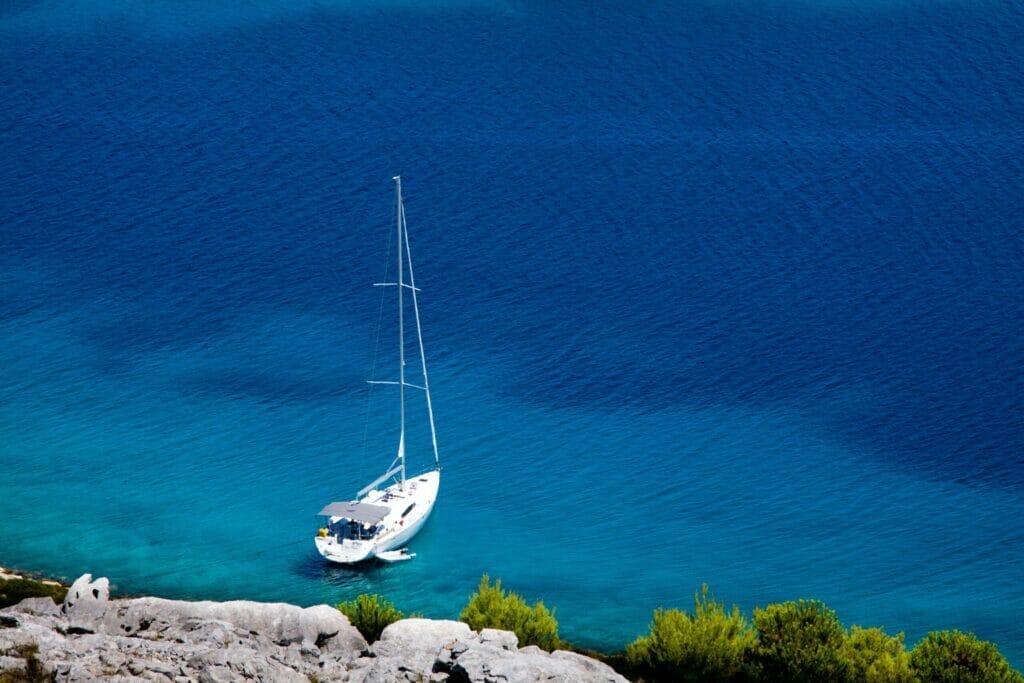 sailboat anchoring close to the shore in crystal clear water