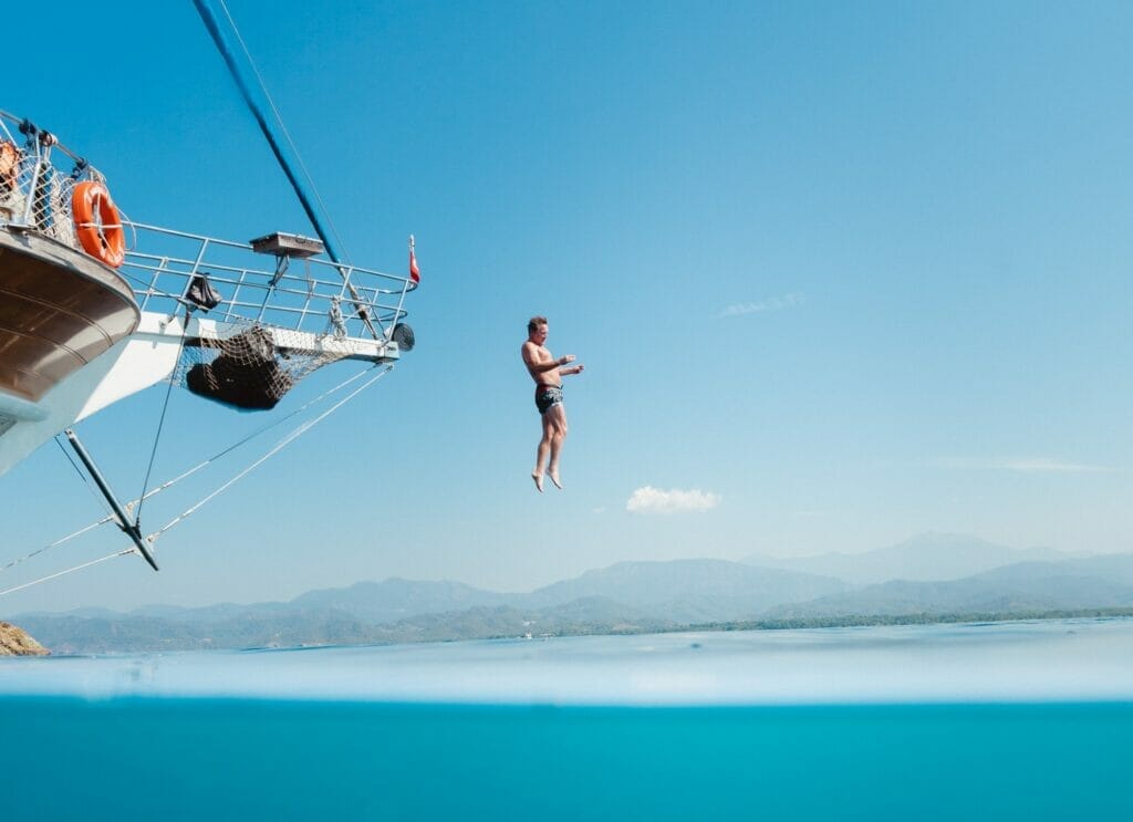 Man jumping off of a boat into the blue paradise waters below.
