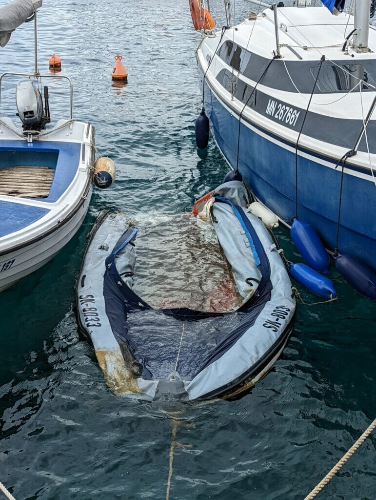 half sunken, end-of-life inflatable boat abandoned in marina