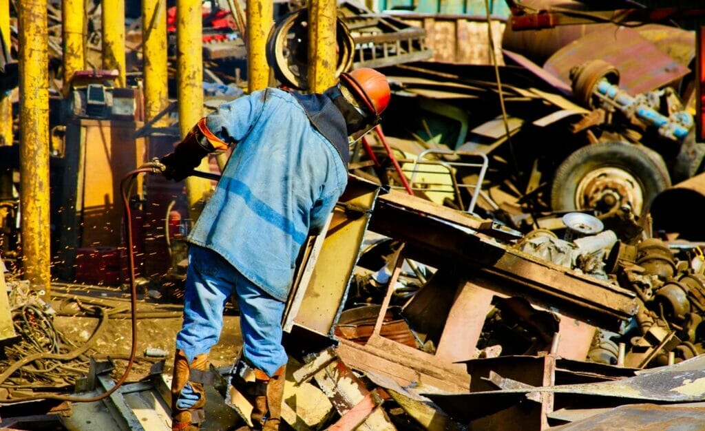 person dismantling metal waste on a scrap yard
