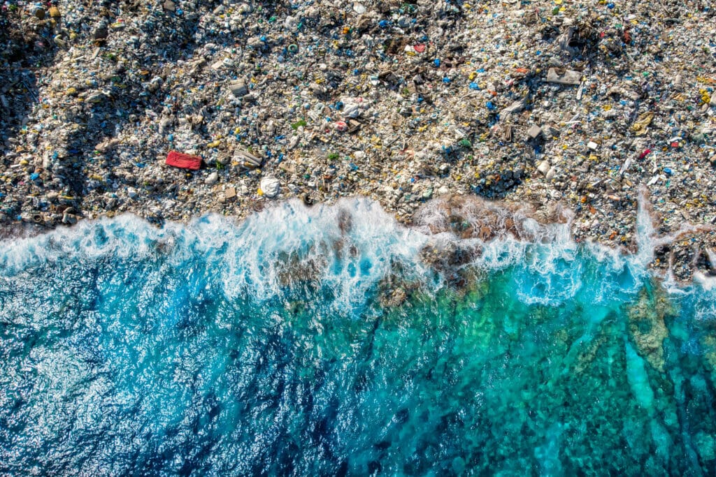 aerial view of polluted coast that is covered with plastic and other waste