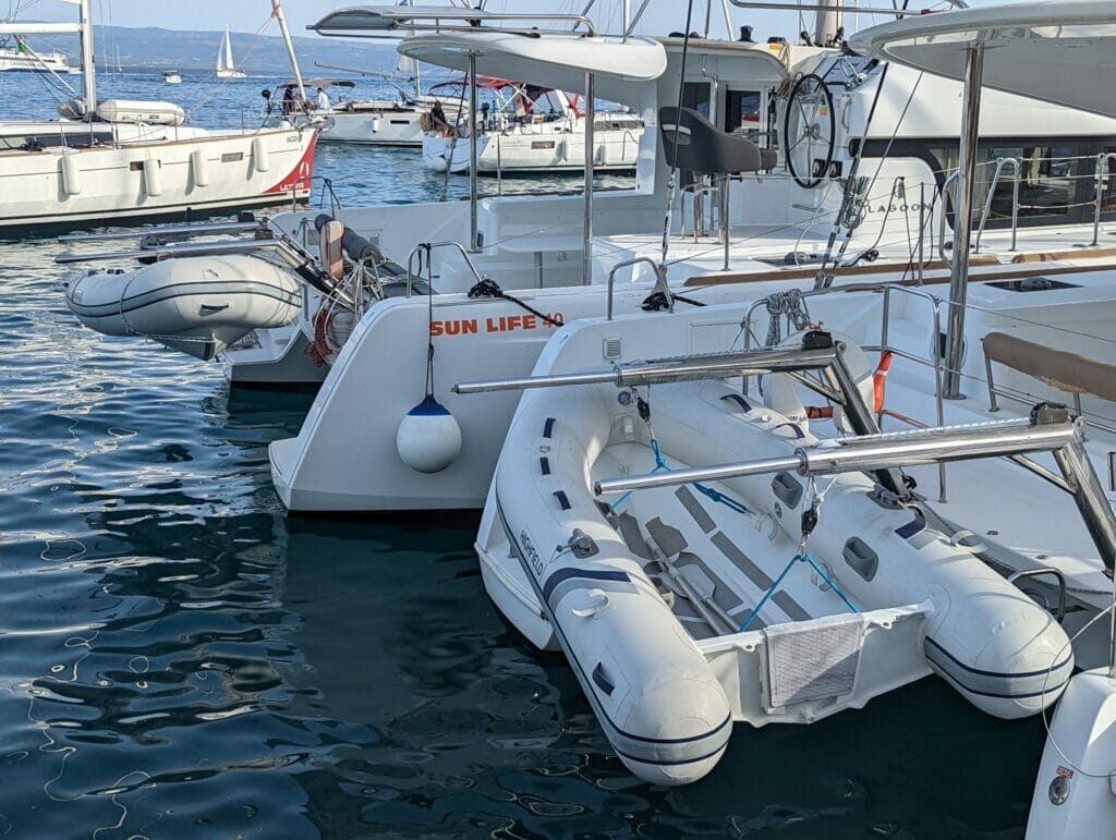 two catamarans with dinghies attached to their davits