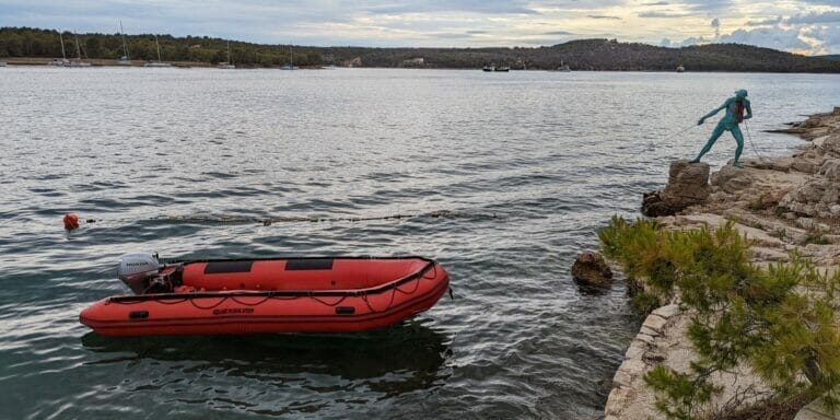 small, soft inflatable boat on a buoy and a statue that seems to be pulling the boat on a rope