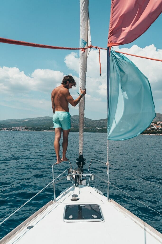 Young man standing on the bow of a sailboat